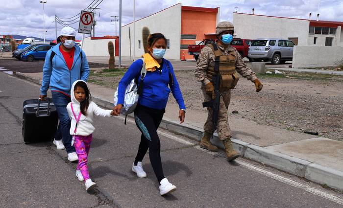 Un soldado chileno escolta a migrantes a las instalaciones policiales, el 15 de febrero, en Colchane, Chile, en la frontera con Bolivia. · Foto: Ignacio Munoz, AFP