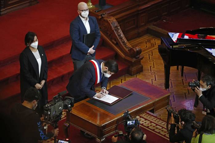 El presidente de Chile, Gabriel Boric, firma el borrador final de la propuesta constitucional durante su presentación en el Congreso Nacional en Santiago. · Foto: Javier Torres AFP