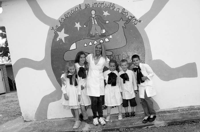 Sofía, Eliana, la maestra Marys López, Milagros, León y Mario posan frente a un mural homenaje a quien da nombre a la escuela, Antoine de Saint-Exupéry. · Foto: Fernando Morán