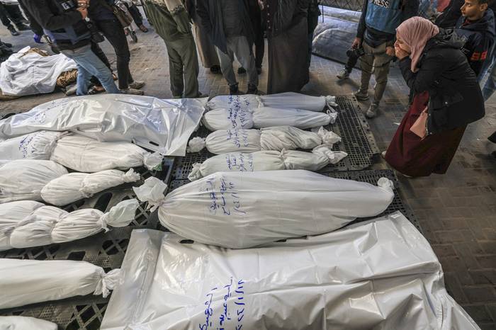 Palestinos junto a los cuerpos de víctimas de un bombardeo israelí, el 18 de enero, en Rafah, en el sur de la Franja de Gaza. · Foto: AFP