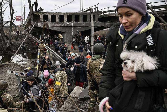 Civiles cruzan un puente destruido ayudados por militares ucranianos, mientras evacuan la ciudad de Irpín, al noroeste de Kiev, el 5 de marzo de 2022. · Foto: Aris Messinis, AFP