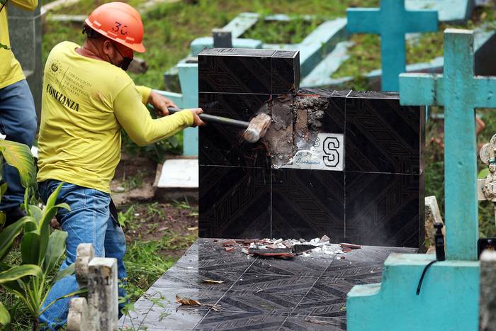 Un recluso destruye una tumba con simbología de la pandilla Mara Salvatrucha (MS-13), en un cementerio en Santa Tecla, El Salvador (03.11.2022). · Foto: Presidencia de El Salvador, AFP