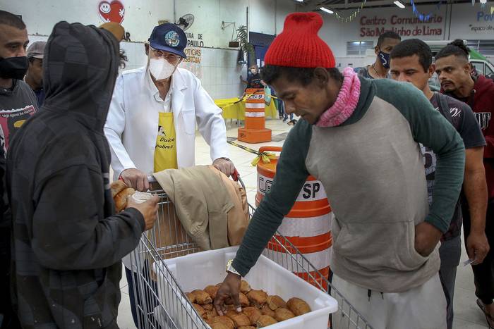 Un sacerdote distribuye alimentos a personas sin hogar en el Centro Comunitario de São Martinho de Lima en San Pablo, Brasil, el 30 de mayo de 2022. · Foto: Felipe Araújo, AFP