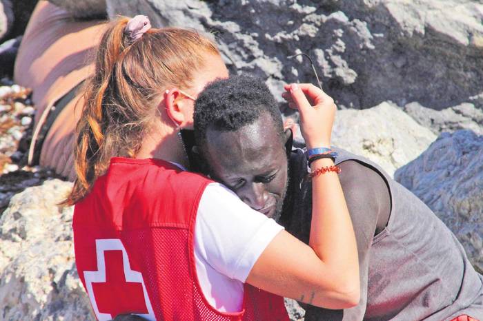 Una trabajadora de la Cruz Roja y un inmigrante que ha logrado cruzar uno de los espigones fronterizos en Ceuta (archivo, mayo de 2021). · Foto: Reduan, EFE