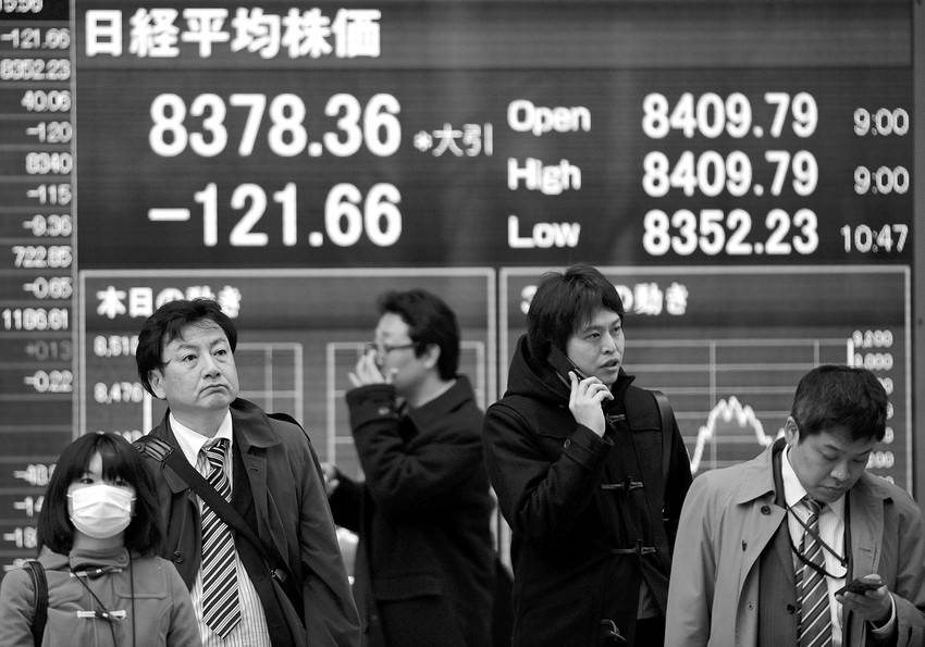 Personas pasan por delante de un monitor con el valor de cierre del indice Nikkei, en Tokio, el lunes.
