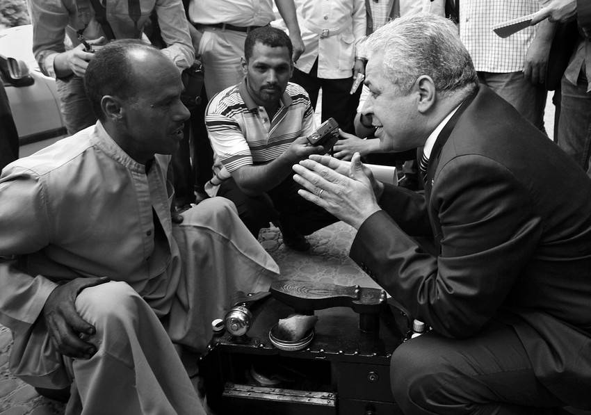 Un candidato a las elecciones presidenciales egipcias, el nacionalista Hamdin Sabahi, charla con un lustrabotas en el último día de campaña electoral, el domingo en El Cairo.