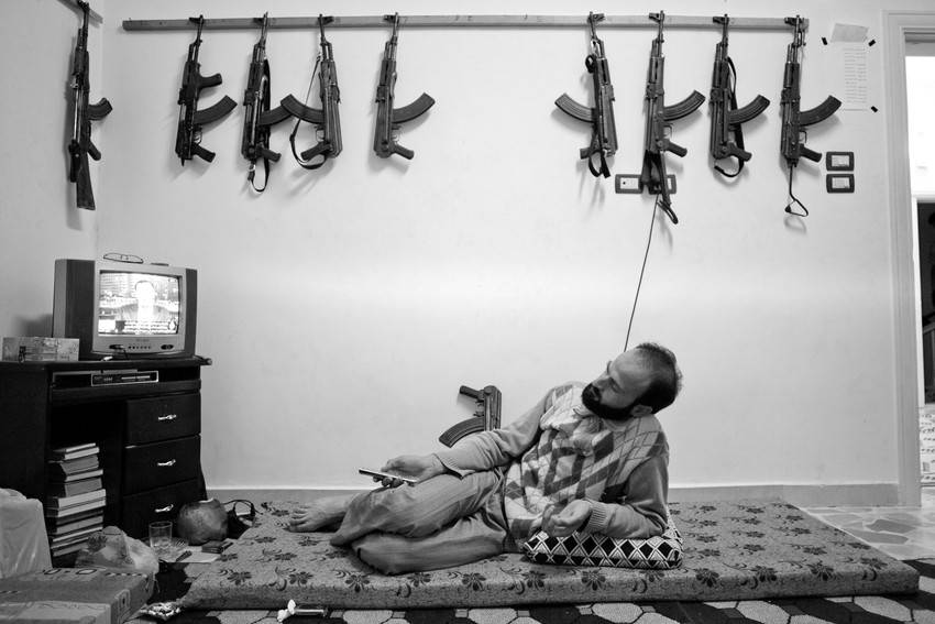 Abu Fida, de 29 años, del rebelde Ejército Libre Sirio (FSA, por sus siglas en inglés), mira televisión junto a varios rifles de asalto Kalashnikov colgados en un muro, en un suburbio de Anadana, norte de Siria. 