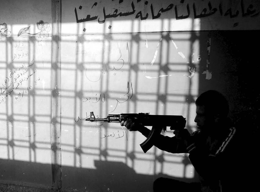 Un rebelde sirio apunta su arma hacia el exterior desde una escuela en Alepo, Siria.