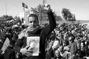 Un simpatizante del líder libio, Muamar el Gadafi, muestra un retrato de Gadafi
ante centenares de refugiados en el paso fronterizo de Ras el Jedir, Túnez.