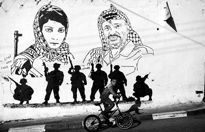 Calle de la ciudad cisjordana de Ramala ayer. En la pared se ve el retrato del ex presidente palestino Yaser Arafat y de la dirigente del Frente Popular para la Liberación de Palestina (FPLP) Leila Khaled. / Foto: Atef Safadi, Efe