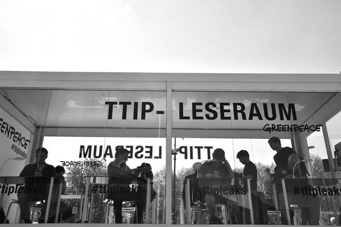La gente lee los folletos sobre las conversaciones de comercio en curso entre Estados Unidos y la Unión Europea, que Greenpeace presenta al público en una cabina de vidrio cerca de la Puerta de Brandeburgo, en Berlín. Foto: John Macdougal