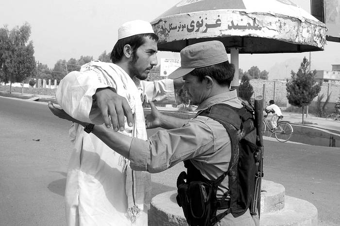 Un oficial de seguridad afgano cachea a un hombre, ayer, en la ciudad natal del mulá Omar, Kandahar, Afganistán. Foto: Muhammad Sadiq, Efe