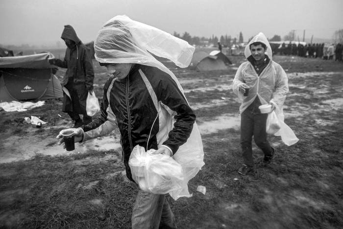 Refugiados llevan comida, ayer, cerca del pueblo de Idomeni, en la frontera entre Grecia y Macedonia. Foto: Zoltan Balogh, EFE