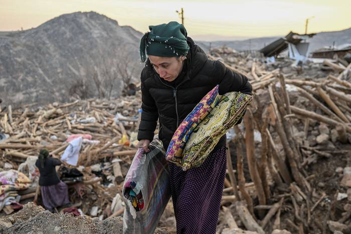 Una mujer recoge pertenencias entre los escombros de su casa derrumbada, en la aldea kurda de Yaylakonak en el distrito de Adiyaman (19.02.2023). · Foto: Bulent Kilic, AFP