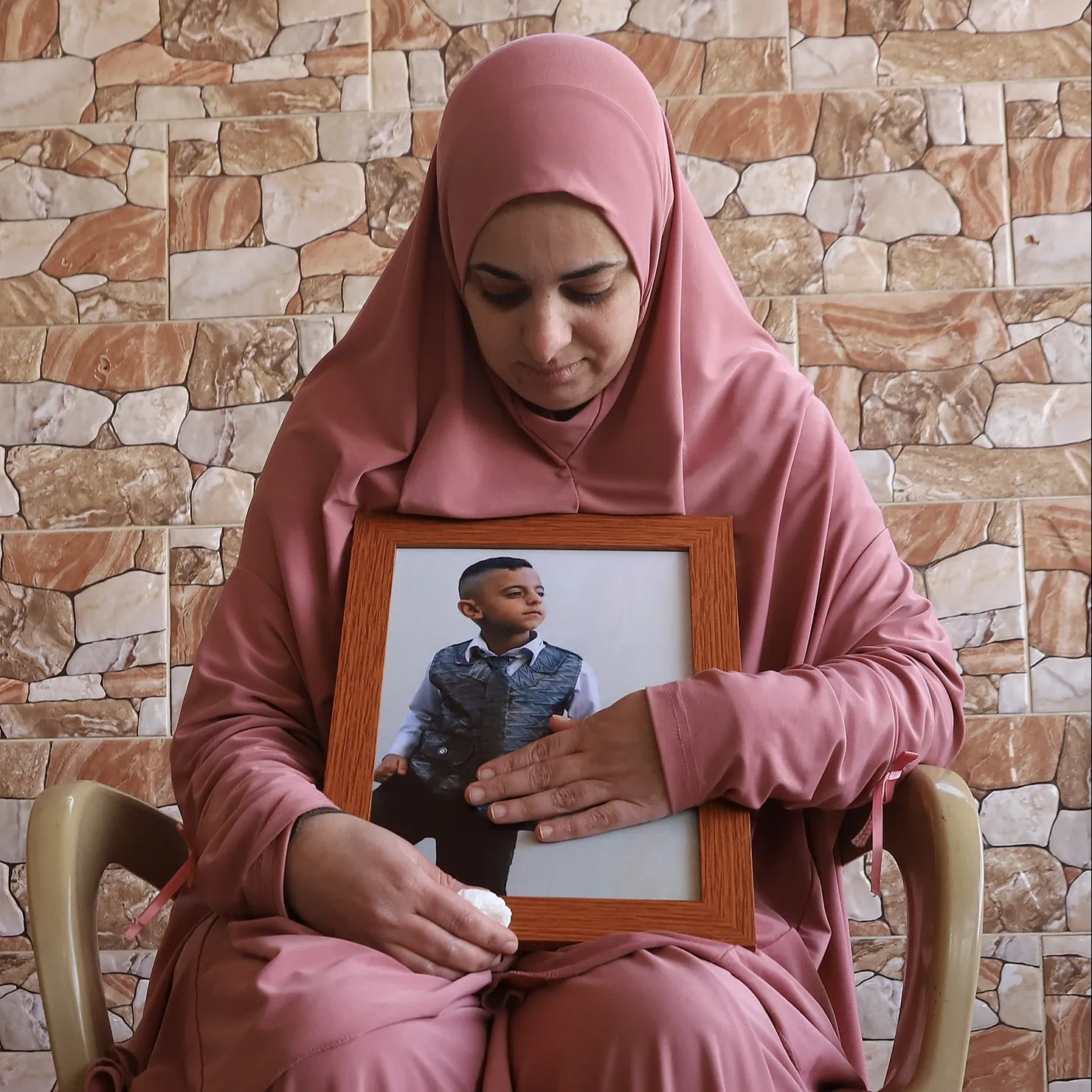 Fidaa Basharat sostiene una fotografía de su hĳo Rida Basharat, quien murió el 8 de enero de 2025 cerca de su casa en un ataque aéreo israelí junto con dos primos: Hamzah y Adam. · Foto: Quique Kierszenbaum