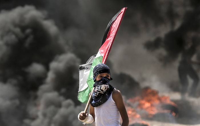 Un jóven palestino observa los enfrentamientos con las fuerzas de seguridad israelíes cerca de la frontera entre Gaza e Israel al este de la ciudad de Gaza, hoy. Foto: Mahud Hams / AFP