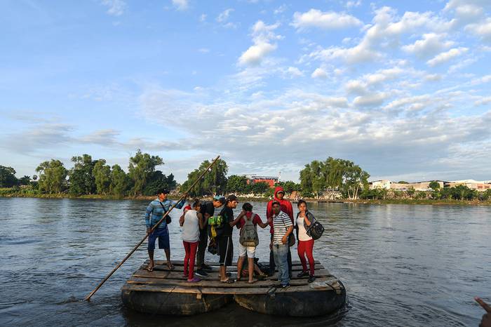 Migrantes hondureños que participan en una caravana que se dirige a los Estados Unidos, cruzan el río Suchiate, frontera natural entre Guatemala y México, en una balsa improvisada, en Ciudad Tecún, Uman, Guatemala. · Foto: Orlando Sierra