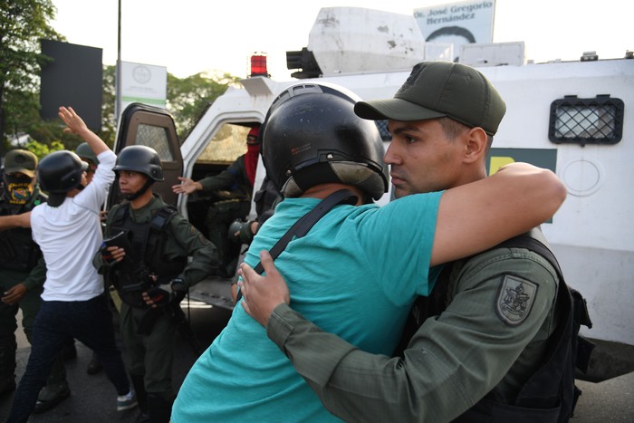 Un venezolano abraza a un integrante de las fuerzas de seguridad hoy en Caracas. Foto: Yuri Cortez / AFP. 