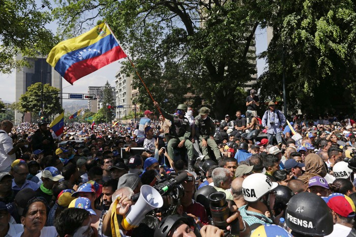 Un integrante de la Guardia Nacional que se unió a la oposición ondea la bandera venezolana durante una movilización en Caracas
 · Foto: Cristian Hernández