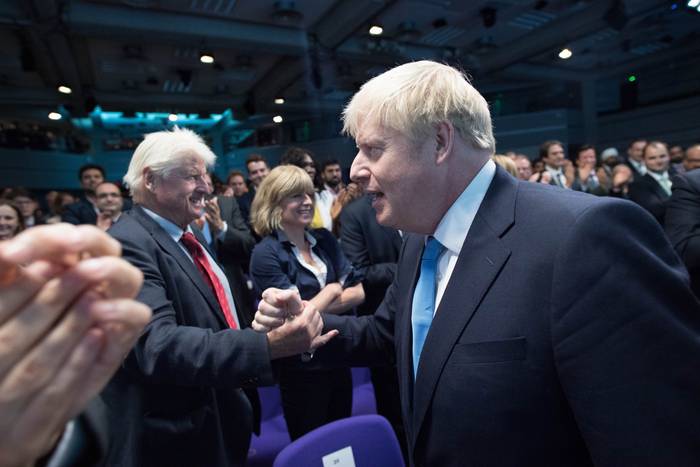 El nuevo primer ministro y líder del Partido Conservador Boris Johnson junto a su padre Stanley Johnson (izquierda) mientras se prepara para dar su discurso luego de los resultados de las internas, el 23 de julio de 2019. Foto: Stephan Rousseau / AFP. 