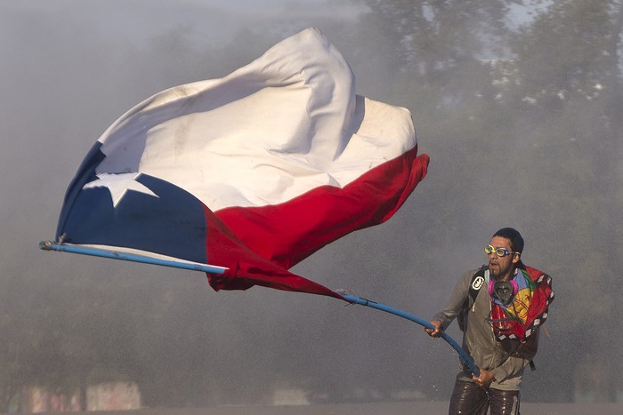 Un manifestante ondea una bandera nacional chilena durante los enfrentamientos con las fuerzas de seguridad luego de una protesta contra el gobierno del presidente chileno Sebastián Piñera en Santiago el 3 de noviembre de 2019.
Claudio Reyes / AFP
