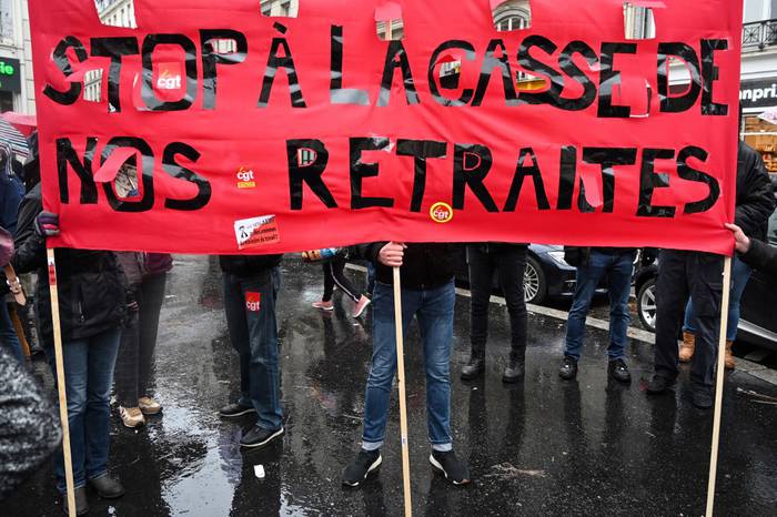 Manifestantes portan una pancarta que dice en francés "No al desmantelamiento de nuestras pensiones" durante una manifestación el 12 de diciembre en París. · Foto: Dominique Faget, AFP