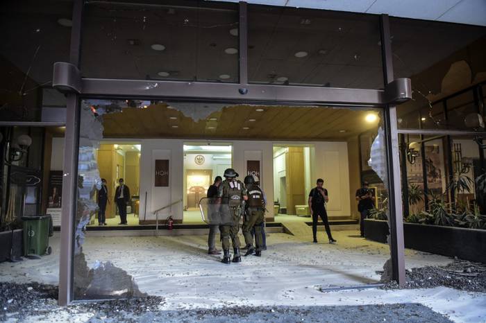 Policías en la puerta del Hotel O'Higgins después de que la entrada del lugar quedara destruida en el marco de los disturbios en las protestas contra el gobierno durante el festival de Viña del Mar. · Foto: Martin Bernetti / AFP