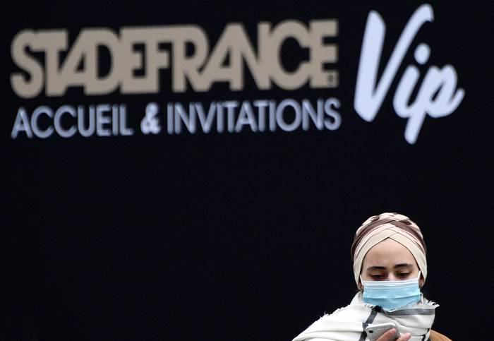 Una mujer con una máscara protectora se ve en la entrada del estadio Stade de France en Saint-Denis, en las afueras de París, el 14 de marzo de 2020. La temporada de fútbol francés se suspendió "hasta nuevo aviso" debido al brote de coronavirus. Franck Fife / AFP
