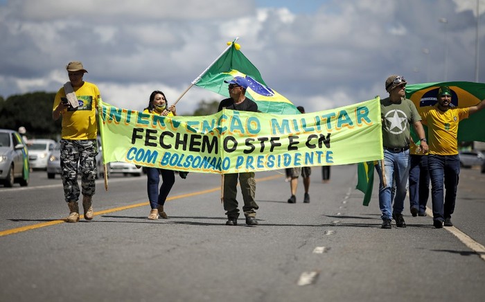 Seguidores del presidente brasileño, Jair Bolonaro, llevan una pancarta pidiendo una intervención militar que cierre el Supremo Tribunal Federal y el Congreso, durante una movilización en la que participó el mandatario.  · Foto: Sergio Lima, AFP