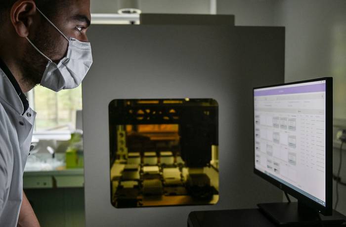 Un miembro del personal médico trabaja con una máquina de reacción en cadena de la polimerasa (PCR), para detectar muestras de COVID-19, el 21 de abril, en el hospital Croix-Rousse, Lyon.  · Foto: Philippe Desmazes, AFP