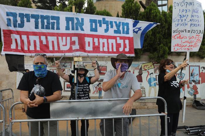 Manifestantes israelíes llevan una pancarta que dice en hebreo "Salvando el país, luchando contra la corrupción" durante una manifestación contra el Primer Ministro Benjamin Netanyahu frente a su residencia en Jerusalén, el 17 de mayo de 2020. Foto: Menahem Kahana / AFP.