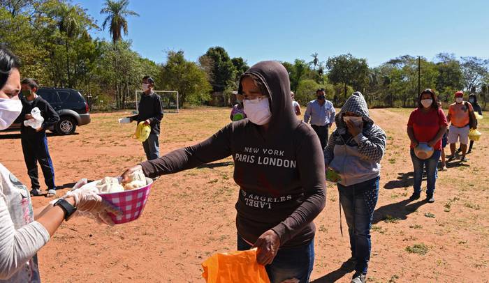 La gente hace cola manteniendo una distancia de seguridad para obtener una comida gratis de voluntarios en Luque, Paraguay, el 17 de mayo de 2020. Foto: Norberto Duarte / AFP.