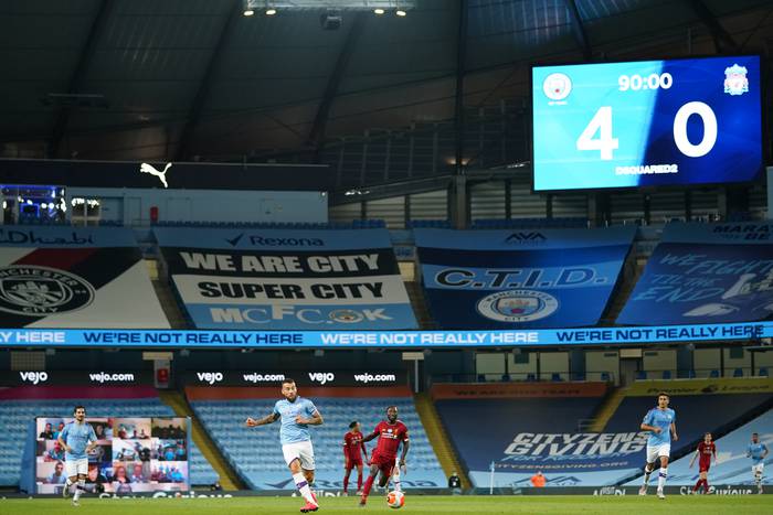 El defensor argentino del Manchester City, Nicolas Otamendi (C), da un pase mientras la pantalla gigante muestra el marcador del partido entre Manchester City y Liverpool, en el estadio Etihad Stadium en Manchester, el 2 de julio de 2020.  Dave Thompson / PISCINA / AFP