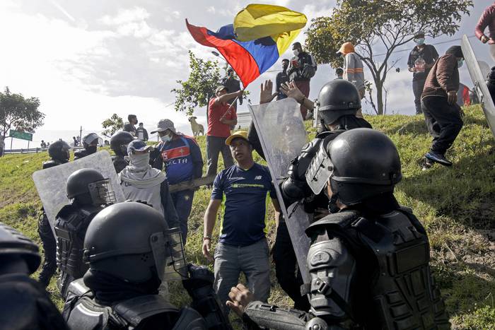 La policía antidisturbios y manifestantes en un bloqueo de carretera en la carretera Ruta Viva, que conduce al aeropuerto Mariscal Sucre, en el marco de protestas lideradas por indígenas contra los altos precios del combustible y el costo de vida, en Quito el 17 de junio de 2022. · Foto: Cristina Vega, AFP