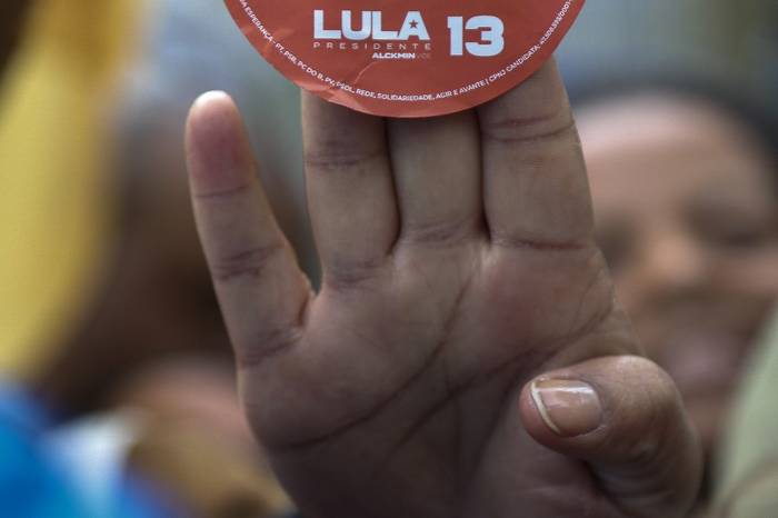 Un simpatizante del candidato presidencial brasileño por el Partido de los Trabajadores (PT) y expresidente (2003-2010), Luiz Inácio Lula da Silva sostiene un cartel durante un acto de campaña, en São Paulo, Brasil, el 20 de agosto de 2022. · Foto: Miguel Schincariol, AFP