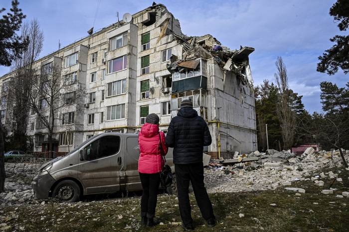 Residentes locales frente a un edificio residencial dañado por un ataque con misiles en la aldea de Kluhyno- Bashkyrivka, región de Kharkiv, el 2 de diciembre de 2022, en medio de la invasión rusa de Ucrania. · Foto: Sergey Bobok, AFP