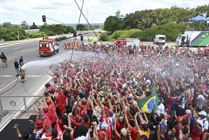 Bomberos rocían agua a la multitud presente en la Explanada de los Ministerios para la asunción de Lula. · Foto: Evaristo Sa, AFP