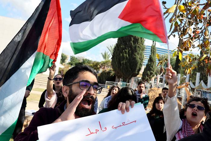 Estudiantes y activistas árabe-israelíes ondean la bandera palestina durante una protesta contra la operación del ejército israelí,