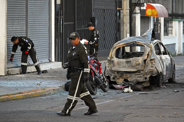 La policía inspecciona los restos de un automóvil después de que explotó, en Quito (31.08.2023). · Foto: Rodrigo Buendía, AFP