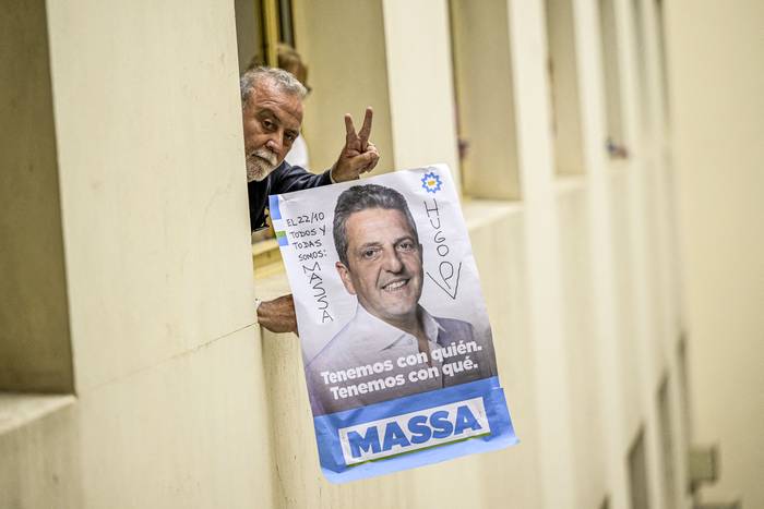 Un trabajador del Ministerio de Economía sostiene un cartel de propaganda electoral de Sergio Massa, mientras espera su llegada para brindar una conferencia con la prensa extranjera, en Buenos Aires (23.10.2023). · Foto: Juan Mabromata, AFP