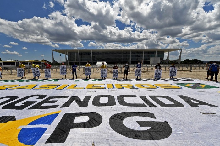 Manifestantes sostienen pancartas durante una protesta contra el gobierno del presidente brasileño Jair Bolsonaro frente al Palacio de Planalto en Brasilia, bajo el lema "Vida, comida, vacuna y educación", el 30 de marzo de 2021. · Foto: Evaristo Sa, AFP