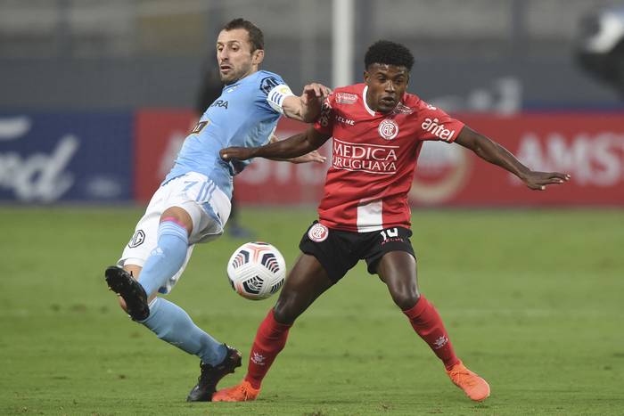 Horacio Calcaterra, de Sporting Cristal, y Leandro Paiva, de Rentistas, durante el partido por Copa Libertadores, el 19 de mayo en el estadio Monumental, en Lima. 


 · Foto: Ernesto Benavides, AFP