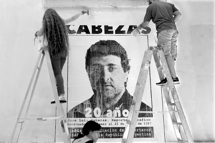 Fotoperiodistas pegan una pancarta de José Luis Cabezas en el 20 aniversario de su asesinato en el antiguo centro clandestino de detención de la Escuela de Marina (ESMA) en Buenos Aires. Foto: Eitan Abramovich / AFP