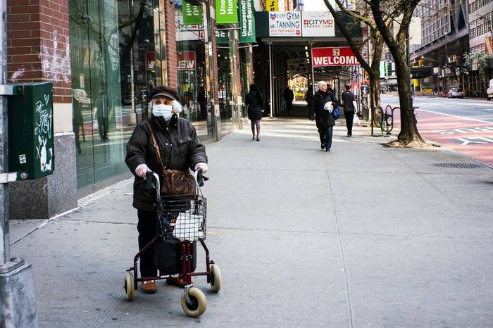 Una anciana usa una máscara facial y guantes de plástico mientras espera cruzar la calle el 26 de marzo de 2020 en la ciudad de Nueva York. Foto: Eduardo Muñoz Álvarez / Getty Images / AFP.