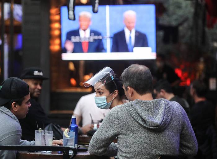 La gente ve una transmisión del debate final entre el presidente Donald Trump y el candidato presidencial demócrata Joe Biden en La Abadía, con asientos al aire libre socialmente distantes, en West Hollywood, California. · Foto: Mario Tama, Getty Images, AFP