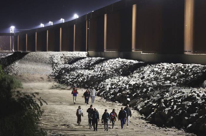 Inmigrantes junto a la cerca fronteriza, luego de cruzar desde México, en Yuma, Arizona. · Foto: Mario Tama, Getty Images, AFP