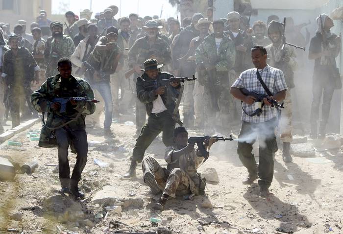 Combatientes del Consejo Nacional de Transición de Libia (CNT) disparan contra fuerzas leales a Muamar Gadafi durante las batallas callejeras en los barrios de Dollar y Número 2 en Sirte, el 17 de octubre de 2011. · Foto: Ahmad Al-Rubaye, AFP