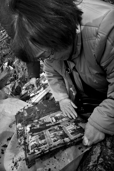 Kuniko Komuro, de 69 años, ayer, mientras quitaba el barro
del álbum de fotos de su nieta cerca de la escuela de enseñanza
primaria de Okawa, en la localidad japonesa de Ishinomaki,
prefectura de Miyagi, una de las zonas afectadas por el terremoto y
posterior tsunami del 11 de marzo. · Foto: Efe, Kimimasa Mayama