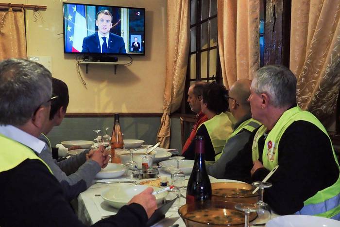 Manifestantes de los llamados "chalecos amarillos", observan el discurso del presidente francés Emmanuel Macron en un restaurante. · Foto: Guillaume Souvant / AFP