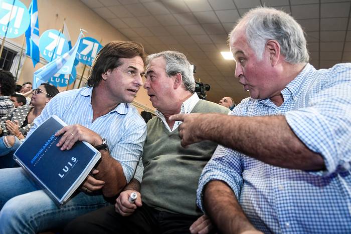 Luis Lacalle Pou, Luis Alberto Heber y Gustavo Penadés durante, durante una acto de campaña, en el Parque Posadas, Montevideo (archivo, mayo de 2019).